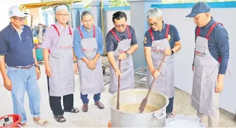  ?? — Photo by Conny Banji ?? Ismail (right) looks on as Dr Annuar (second right) and Wan Azhan stir the Bubur Asyura.