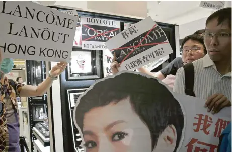  ?? Kin Cheung / Associated Press ?? Protesters display a picture of singer Denise Ho on Wednesday at a Lancome counter in a Hong Kong department store. French cosmetics company Lancome has sparked a backlash after it canceled a promotiona­l concert featuring a singer known for...