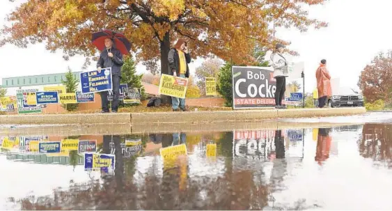  ?? BRIAN KRISTA/BALTIMORE SUN MEDIA GROUP ?? Citizens deal with the rainy weather while electionee­ring near Elkridge Elementary School during Election Day in Howard County.