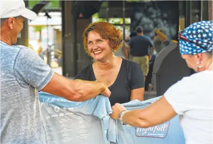  ?? STAFF PHOTO BY TIM BARBER ?? Carla Pritchard makes the decisions for the Nightfall Series in Miller Plaza and is seen here selling T-shirts on a recent Friday night concert.