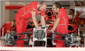  ?? AP ?? The crew for Ferrari driver Sebastian Vettel assembles the car for the Formula One US Grand Prix. The German had suffered an engine failure in Malaysia that left him last on the grid. —