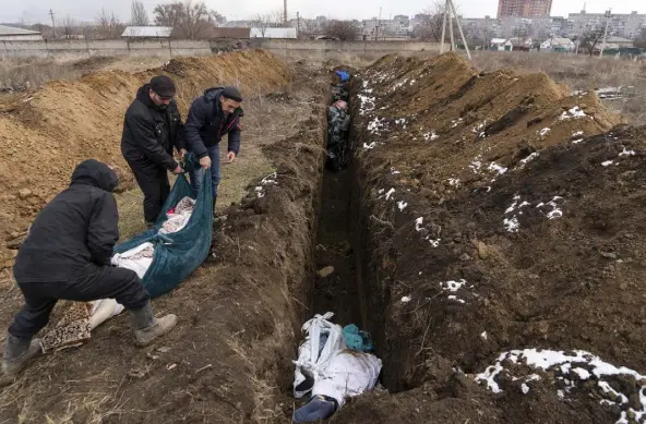  ?? Photos by Mstyslav Chernov, The Associated Press ?? Dead bodies are placed into a mass grave on the outskirts of Mariupol, Ukraine, on March 9 as people cannot bury their dead because of heavy shelling by Russian forces.