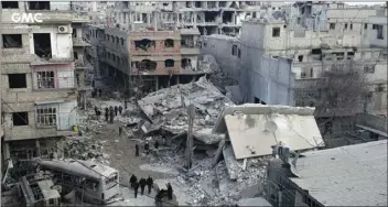  ??  ?? In this photo released on Thursday which provided by the Syrian anti-government activist group Ghouta Media Center, which has been authentica­ted based on its contents and other AP reporting, shows Syrians gather between destroyed buildings which...