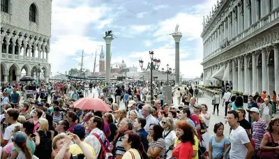  ??  ?? La folla di turisti in piazza San Marco a Venezia. Ogni anno i visitatori sono 28 milioni e potrebbero crescere ancora.