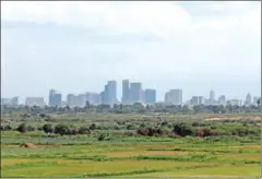  ?? HONG MENEA ?? The skyscraper­s of Phnom Penh can be seen in the distance, towering above lush green fields, in May last year.