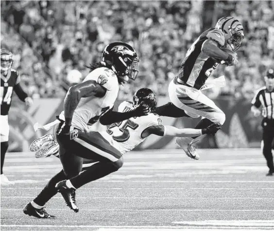  ?? FRANK VICTORES/ASSOCIATED PRESS ?? Bengals running back Joe Mixon, right, leaps from the hands of Ravens cornerback Tavon Young in the first half. Mixon gained 84 yards rushing on 21 carries for Cincinnati.