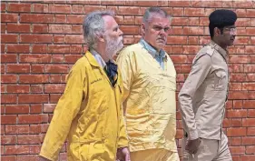  ?? HADI MIZBAN/AP ?? Jim Fitton of Britain, left, and Volker Waldman of Germany are escorted by Iraqi security forces outside a courtroom in Baghdad on May 22.
