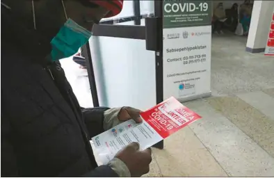  ??  ?? A volunteer reads an informatio­n leaflet while waiting to be administer­ed the new Chinese-made vaccine for the Covid-19 coronaviru­s, the first ever Phase 3 clinical trial for any vaccine in Pakistan, at a hospital in Islamabad.