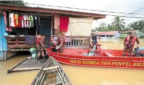  ?? ?? To higher ground: Fire and rescue department personnel evacuating flood victims from Kampung Muhibbah to a temporary evacuation centre in Bukit Garam. — Bernama