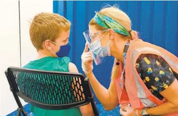  ?? ULYSSES MUÑOZ/BALTIMORE SUN ?? Rachael Cannaday prepares Ryan Johnston, 8, to get his COVID-19 vaccine at the White Marsh Mall on Friday, telling him to keep his eyes on her instead of the needle.