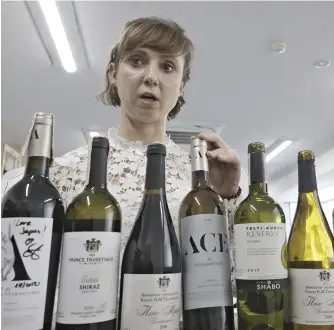  ?? The Yomiuri Shimbun ?? Ukrainian Anna Vasia, who prays for peace in her home country, stands besides Ukrainian wine products in Yokohama on March 15.