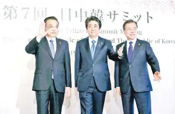  ?? — Reuters photo ?? (From left) Li Keqiang, Shinzo Abe and Moon Jae-in pose for photograph­ers prior to their summit in Tokyo.