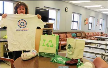  ?? KRISTI GARABRANDT — THE NEWS-HERALD ?? Bonnie Rice, Keep Mentor Beautiful executive director and solid waste coordinato­r for Mentor’s Public Works Department, shows unexpected items such as T-shirts, canvas tote bags, tennis shoes and ink pens all made from recycled plastic bottles.