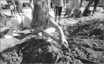  ?? AP PHOTO ?? Chloe Heeden, 4, from Virginia Beach, Va., shovels sand to help her dad fill sandbags Wednesday in Virginia Beach, Va., as Hurricane Florence moves towards the eastern shore.