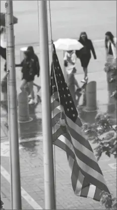  ?? PAUL BEATY/AP ?? A UNITED STATES FLAG flies at half-staff after a Fourth of July parade shooting in nearby Highland Park, Ill., while lines of fans wait to go through added security at Guaranteed Rate Field on Monday in Chicago before a game between the Chicago White Sox and the Minnesota Twins.