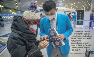  ?? MARK SCHIEFELBE­IN AP ?? A worker helps a traveler fill out an electronic declaratio­n of their COVID-19 health status in the internatio­nal arrivals area at Beijing Capital Internatio­nal Airport on Jan. 9.