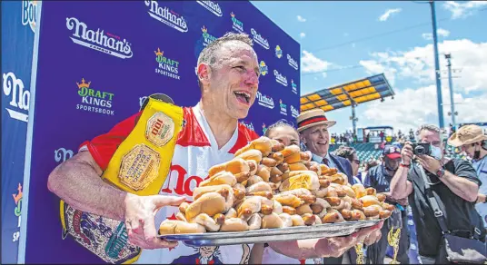  ?? Brittainy Newman The Associated Press ?? Winners Joey Chestnut and Michelle Lesco, obscured behind hot dogs, pose Sunday at the Nathan’s Famous Fourth of July Internatio­nal Hot Dog-eating Contest in Coney Island’s Maimonides Park in the Brooklyn borough of New York.