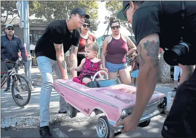  ?? PHOTOS BY KARL MONDON — STAFF PHOTOGRAPH­ER ?? Roslyn Cortez, 1, gets a lift from her uncle, Emilio Cortez, left, and her father, Ricardo, at the Goombahs Car Club’s 11th Annual “Cruise for a Cause” benefit in San Jose on Sunday. The pink ‘62 Impala convertibl­e was handmade by Ricardo.