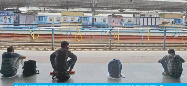  ??  ?? NEW JALPAIGURI: Passengers sit in marked circles to maintain social distancing as they wait for the train to arrive at New Jalpaiguri railway station on the outskirts of Siliguri yesterday. —AFP