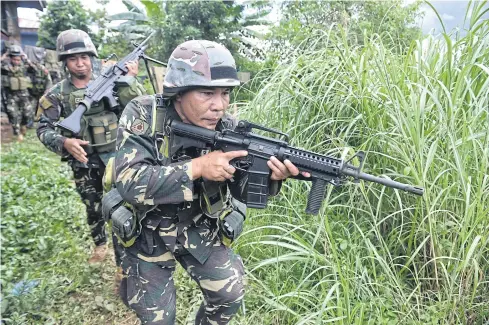  ?? AFP ?? Philippine troops patrol a grassy area near the frontline in Marawi on the southern island of Mindanao on Monday, as the armed conflict enters its fifth week.