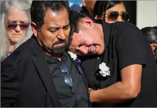  ?? ?? As a hearse leaves, Alejandro Lopez, left, and his son Giovanni Lopez-Ruano mourn the death of Giovanni's godfather, Marciano Martinez, after his funeral at Our Lady of the Pillar Catholic Church in Half Moon Bay.