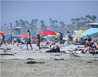  ?? Los Angeles Times/tns ?? Beachgoers enjoy the sunshine near the pier in Huntington Beach, California, on Friday, Sept. 4, 2020.