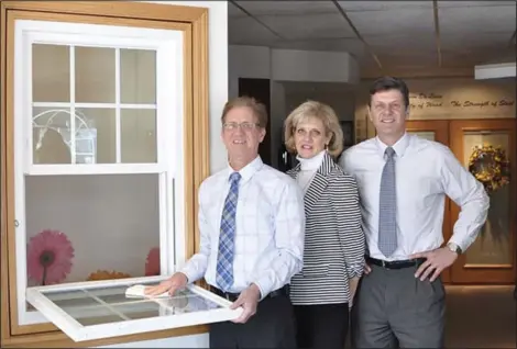  ?? COURTESY OF DELUXE WINDOW & DOOR ?? Harry Jr., left, Joni and Mike Dennis, co-owners of DeLuxe Window & Door, demonstrat­e how easy it is to clean a tilt-in window.