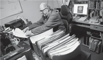  ?? TIM KROCHAK • SALTWIRE NETWORK ?? Retired Canadian military veteran Tim Dunne looks over some of the documents related to his military career in the basement office of his Dartmouth home April 22, 2022.