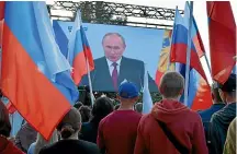  ?? AP ?? People in SaurMogila in the separatist Donetsk People’s Republic watch Russian President Vladimir Putin announce the absorption of four regions of eastern Ukraine into Russia.