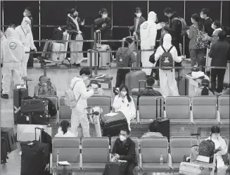  ?? YIN LIQIN / CHINA NEWS SERVICE ?? Staff check informatio­n about inbound travelers at Shanghai Pudong Internatio­nal Airport before transporti­ng them to designated quarantine venues on Sunday.