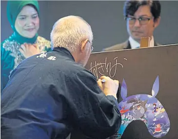  ??  ?? Studio Ghibli producer Toshio Suzuki signs a poster during the launch of World of Ghibli in Jakarta in April.