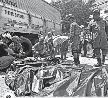  ?? PHOTO BY MACKY LIM ?? IDENTIFY. Relatives together with Central 911 rescuers identify the bodies laid on the ground after yesterday’s road accident in Km.5 Guadalupe, Matina Pangi in Davao City that killed nine including a three-year-old boy.