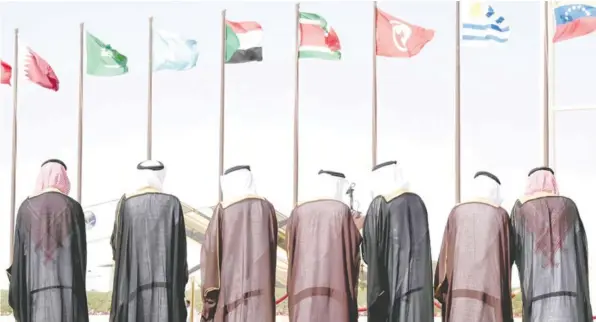  ??  ?? RIYADH: Saudi officials stand in front of the flags of countries being hosted by Saudi Arabia to attend the 4th summit of Arab States and South American countries, during the welcoming ceremony held at King Khalid Internatio­nal airport in Riyadh yesterday. — AFP