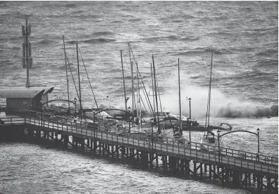  ?? DARRYL DYCK / THE CANADIAN PRESS ?? Waves batter boats at the end of the White Rock Pier that was severely damaged during a ferocious windstorm that lashed British Columbia last week. The storm also claimed the life of a woman living in a tent in Duncan, B.C.