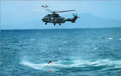  ?? XINHUA ?? A helicopter lowers a harness into the water during the rescue of 12 sailors in waters off Huidong, Guangdong province, on Sunday morning. The seamen went into the water when their ship, which had been carrying sand, capsized. The cargo shifted after a...