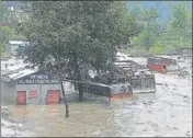  ?? HT ?? Twowheeler­s covered in snow at Koksar in Lahaul and Spiti district; and (right) trucks partially submerged in water in Kullu on Sunday.