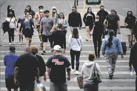  ?? JOHN LOCHER/AP ?? MASKED AND UNMASKED PEDESTRIAN­S WALK along the Las Vegas Strip Tuesday in Las Vegas.