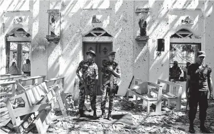  ??  ?? Sri Lankan soldiers inside the St Sebastian’s Church at Katuwapiti­ya in Negombo yesterday following a bomb blast during the Easter Sunday service. A series of eight devastatin­g bomb blasts ripped through high-end hotels and churches holding Easter services. Over 200 people were killed, including foreigners. — AFP