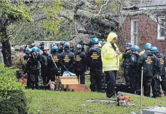  ?? CHUCK LIDDY THE ASSOCIATED PRESS ?? Rescue workers, police and fire department members wait to remove the bodies of a mother and child who were killed by a falling tree as hurricane Florence made landfall in Wilmington, N.C. Friday .