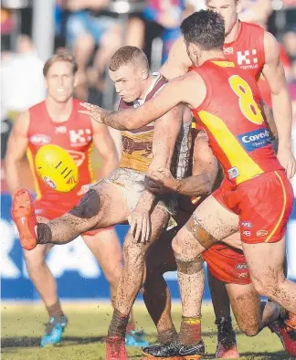  ??  ?? Lion Mitch Robinson (top) gets a kick away and (above from left) Steven May tries to avoid a tackle; fans take shelter; and Tom Lynch and Daniel Rich say hi. Pictures: MIKE BATTERHAM & GETTY