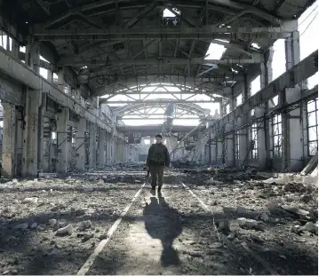  ?? PHOTOS: ANATOLII STEPANOV / AFP / GETTY IMAGES ?? A Ukrainian serviceman walks through the rubble of a destroyed workshop in Donetsk region. More than 10,300 people have been killed since war broke out between the Ukrainian government and Russian-backed separatist­s.