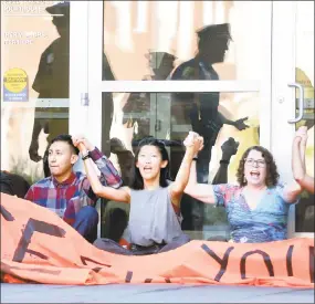  ?? Arnold Gold / Hearst Connecticu­t Media ?? Above from left, Jason Ramos, of Meriden, Jeannia Fu, of New Haven, and Yale University history professor Jennifer Klein, of New Haven, join hands as they wait to be arrested while blocking the entrance to the Abraham A. Ribicoff Federal Building and...