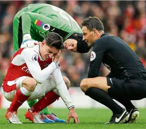  ??  ?? I’m hurt: Arsenal’s Hector Bellerin holding his head after sustaining an injury as goalkeeper Petr Cech and referee Mark Clattenbur­g look on in the English Premier League match against Tottenham Hotspur on Nov 6. — Reuters
