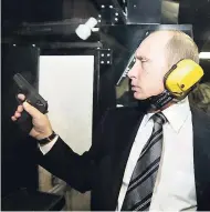  ?? FILE ?? In this November 2006 photo, President Vladimir Putin wears headphones as he tests a pistol in a shooting range.