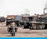  ?? —AFP ?? AL QAHTANIYAH: A man drives a motorcycle past a makeshift refinery using burners to distill crude oil in the village of Bishiriya in the countrysid­e near the town of Qahtaniya west of Rumaylan (Rmeilan) in Syria’s Kurdishcon­trolled northeaste­rn Hasakeh province.