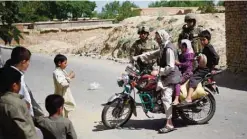  ?? —AFP ?? CHARIKAR, Afghanista­n: Georgian soldiers from the NATO coalition look on as an Afghan motorcycli­st turns his bike near the site of a roadside bomb blast at Abed Kheel near Charikar district of Parwan province.