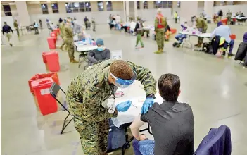  ?? — AFP photo ?? A member of the US Armed Forces administer­s a Covid-19 vaccine at a FEMA community vaccinatio­n centre in Philadelph­ia, Pennsylvan­ia.