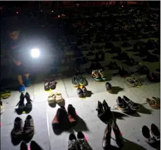  ?? AP Photo/Ramon Espinosa ?? In this June 1 file photo, a child shines a light on hundreds of shoes at a memorial for those killed by Hurricane Maria, in front of the Puerto Rico Capitol in San Juan.