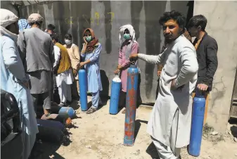  ?? Rahmat Gul / Associated Press ?? People wait outside a privately owned oxygen plant in Kabul to get their cylinders refilled. Officials say Afghanista­n is fast running out of oxygen as a surge of coronaviru­s worsens.