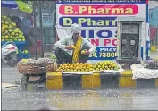  ??  ?? A mango seller braves rain to sell the fruits on Monday.